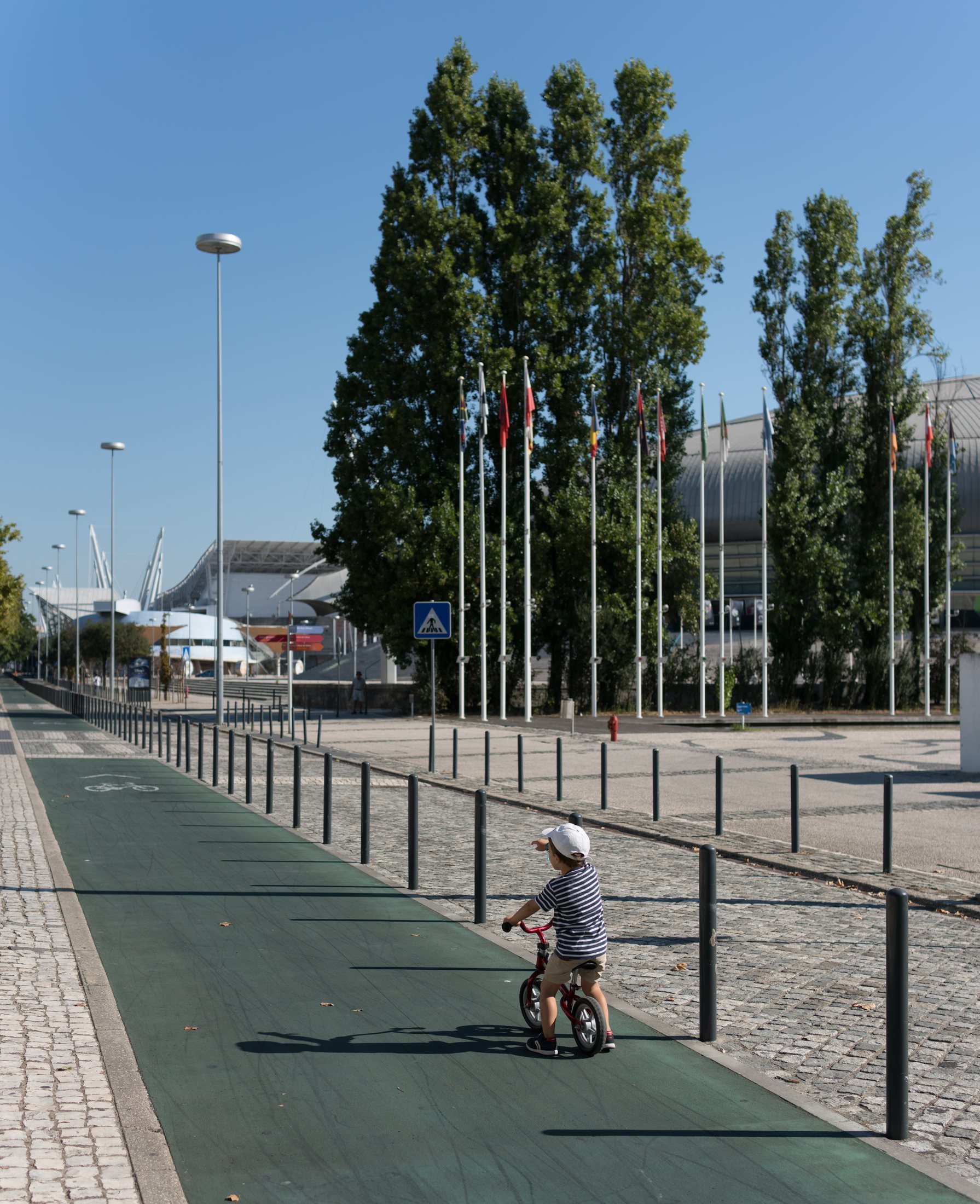 A young child using a balance bike on a marked cycle path.