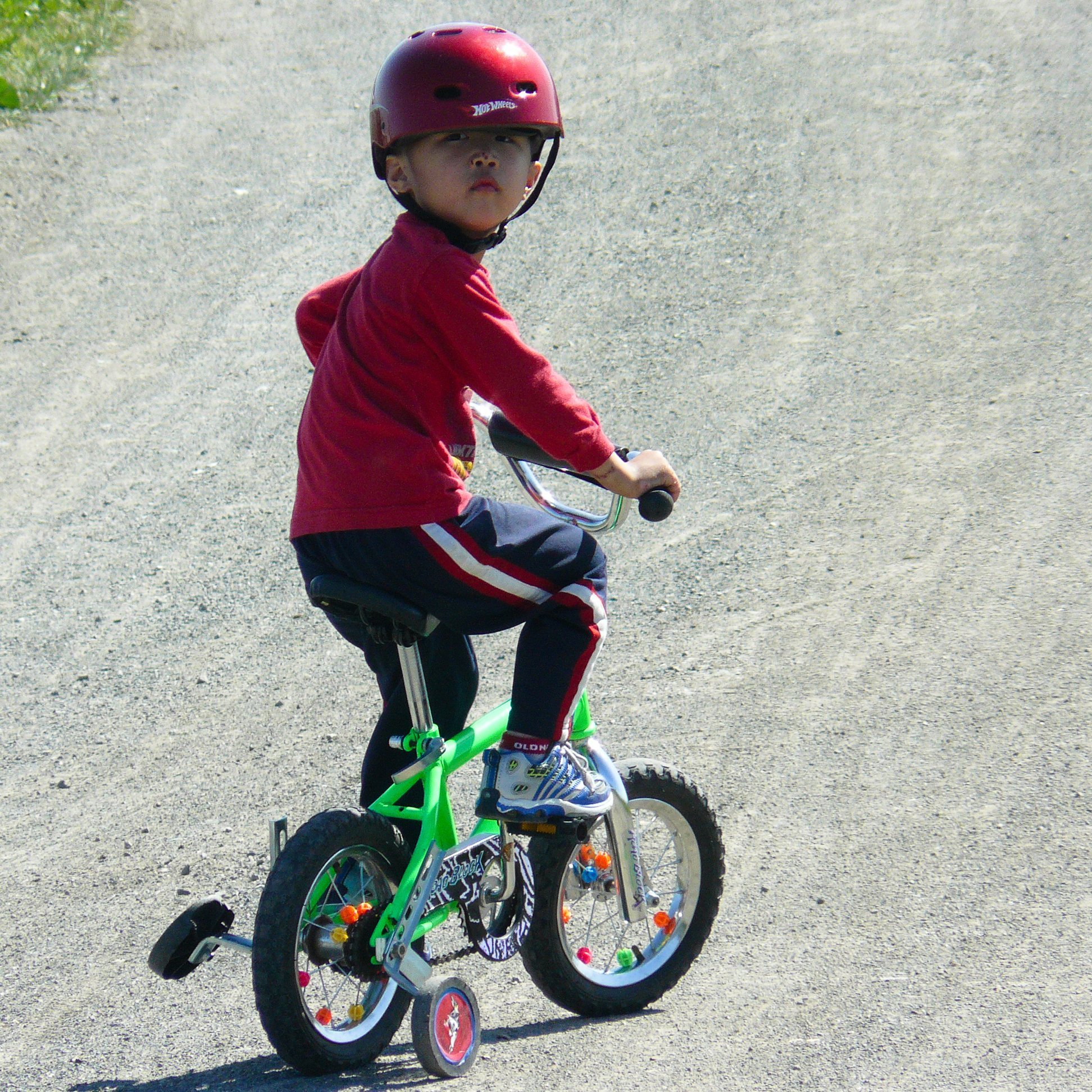 A helmeted child riding a small bicycle with training wheels.