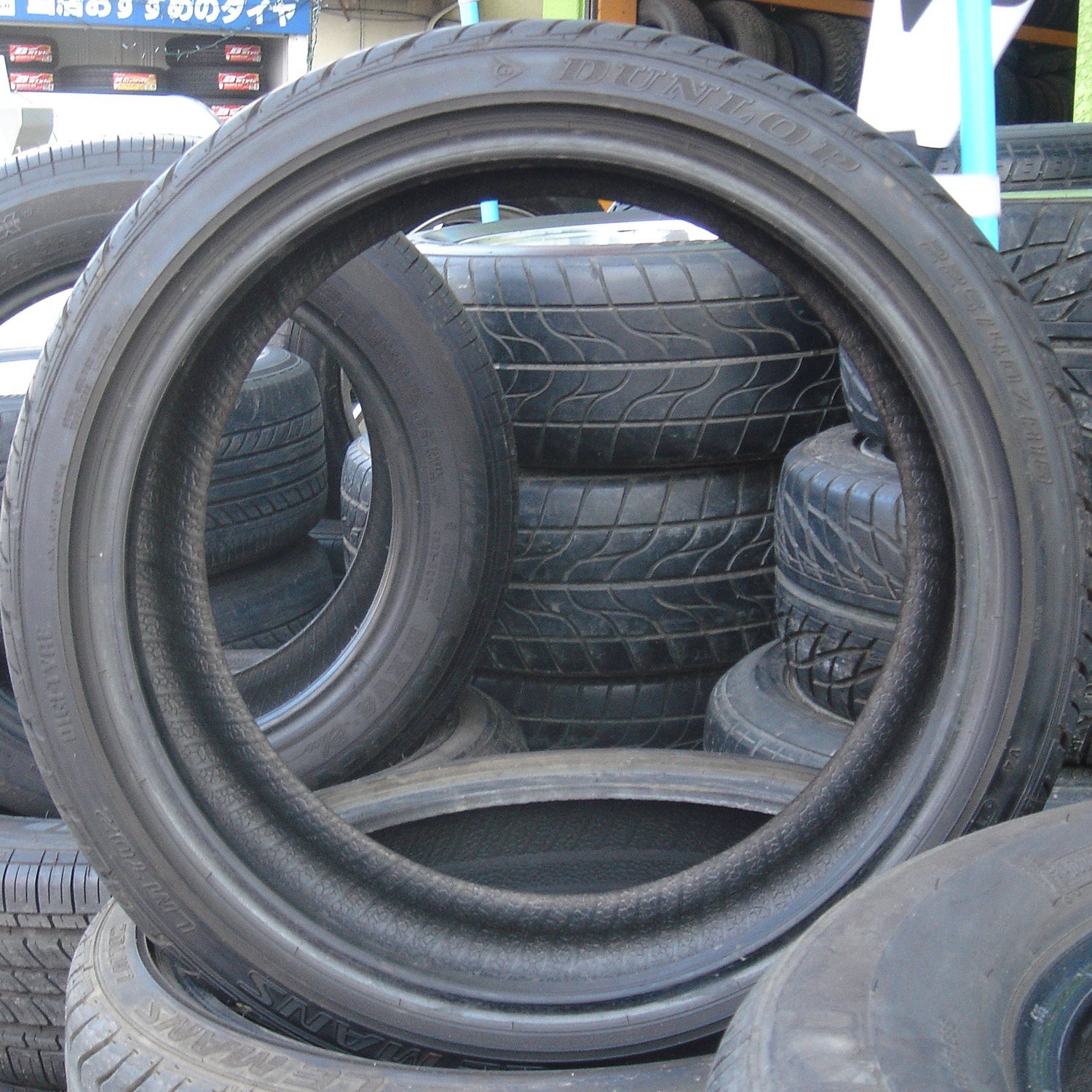 Many black car tires stacked and standing at a tire store.