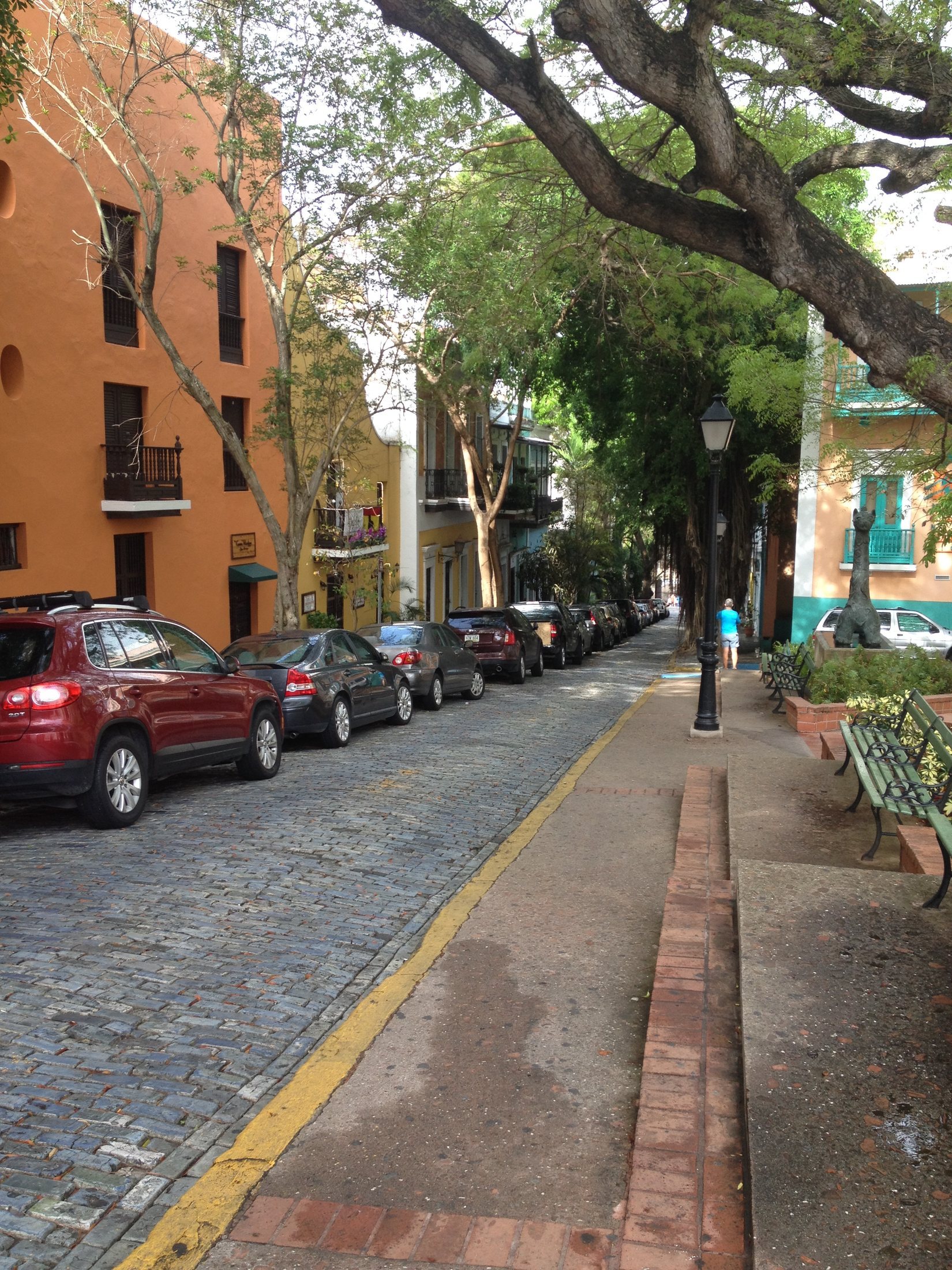 Cars parked along a colorful street with buildings beside the road.