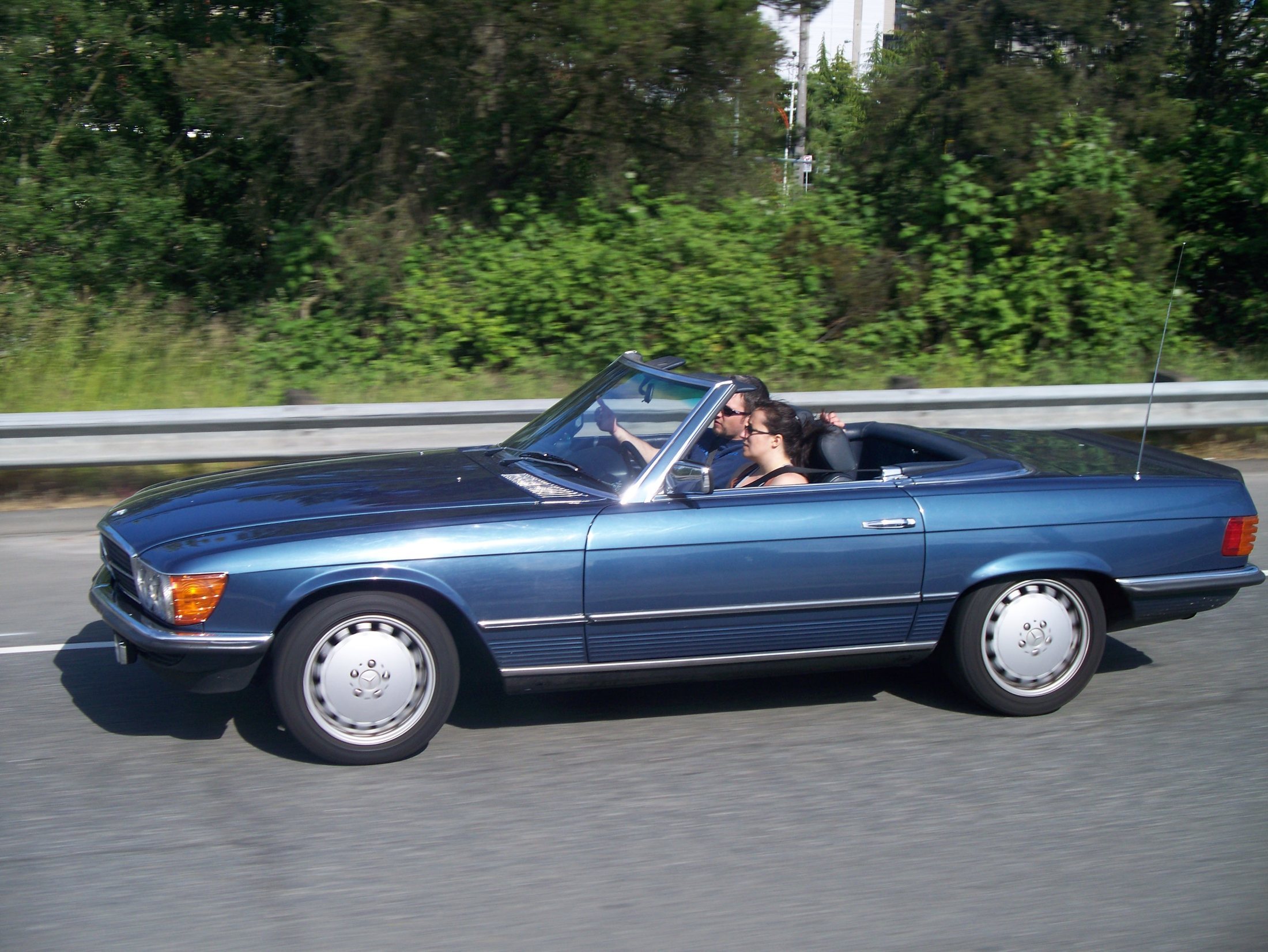 A convertible car driving on a highway road.