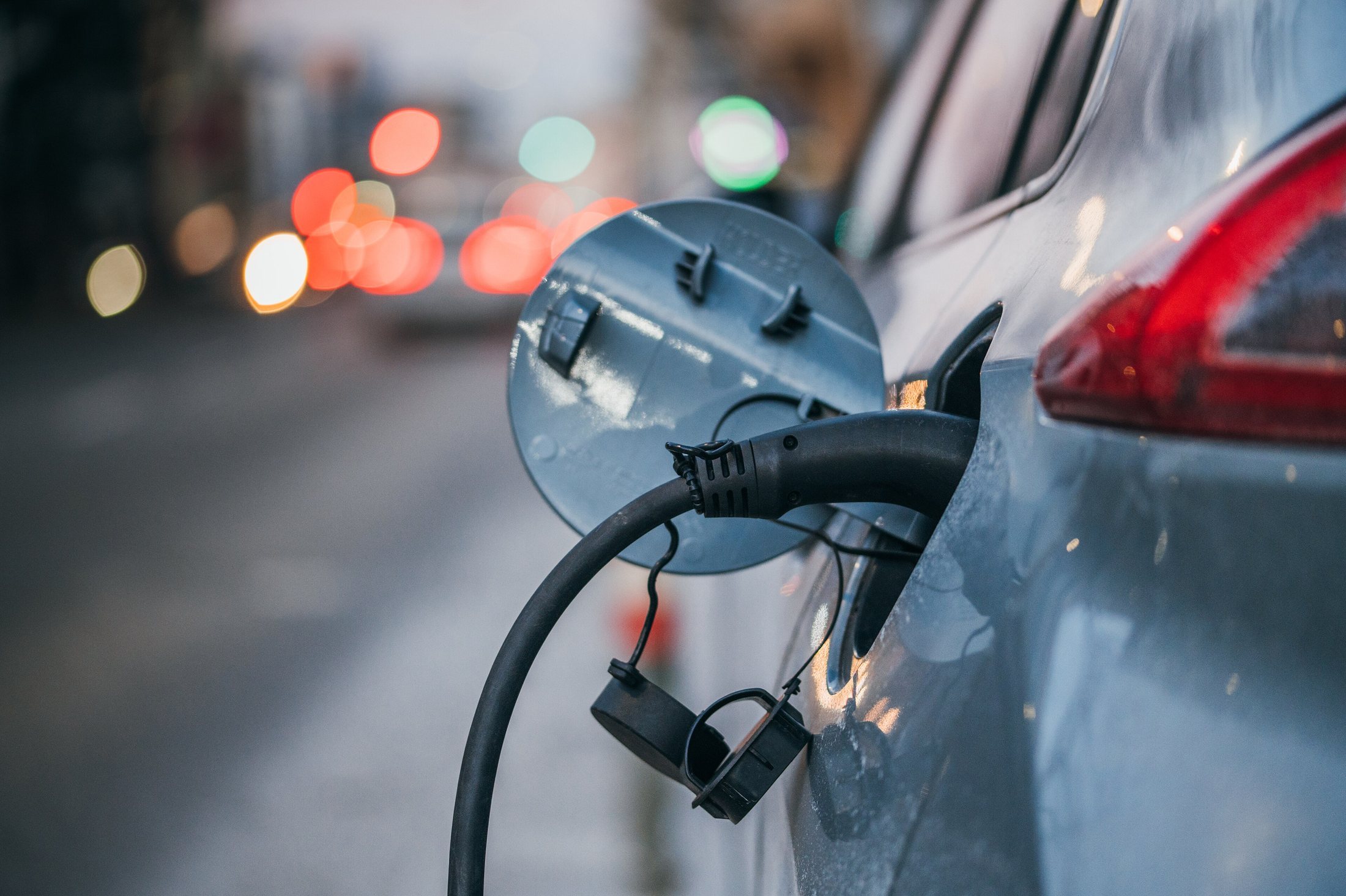 A close-up of an electric car plugged in to charge.