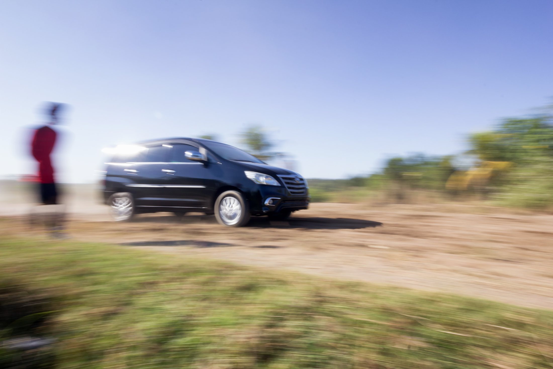 A tall SUV driving on a dusty road.