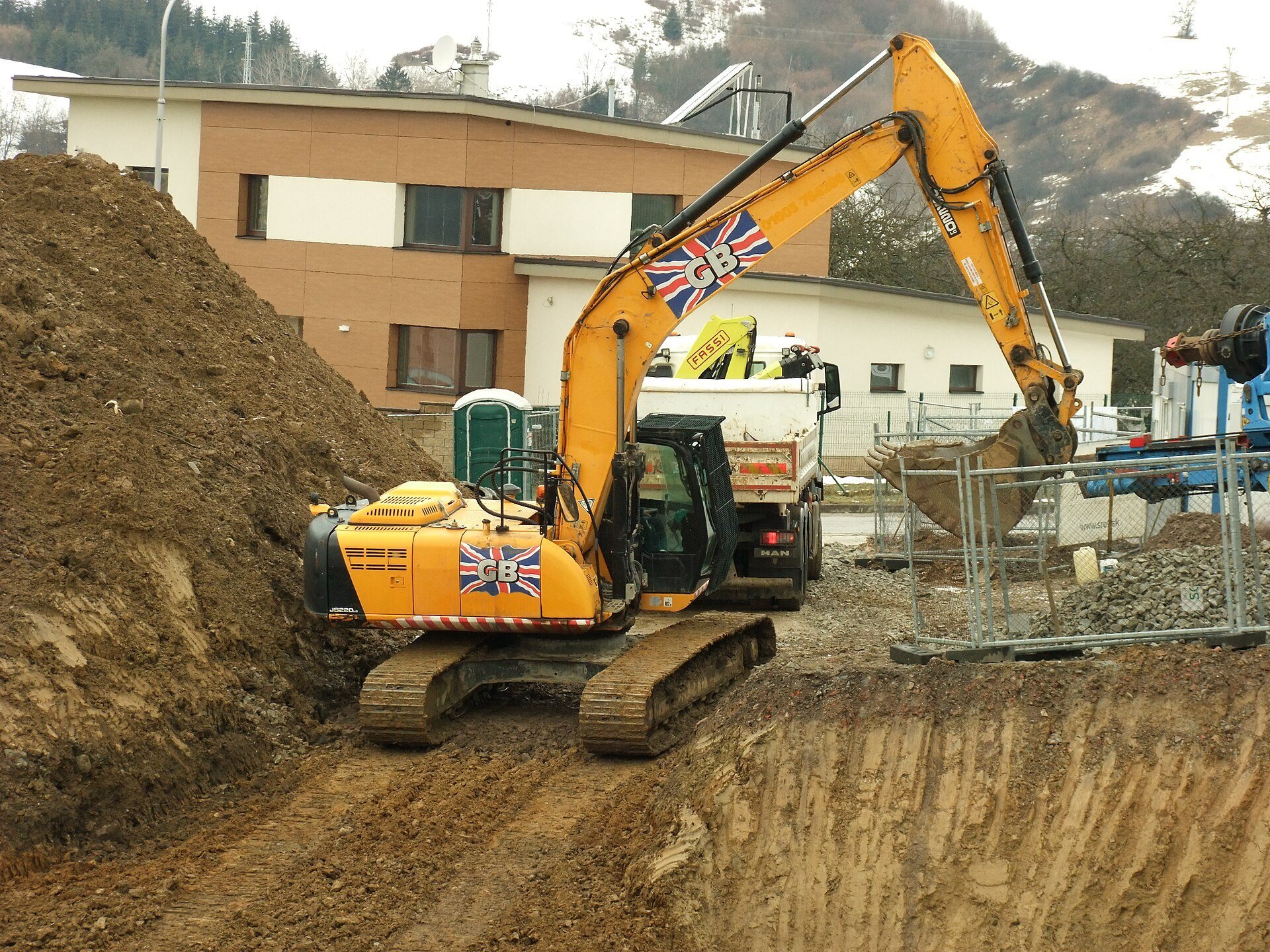 A JCB tracked excavator actively digging at a construction site