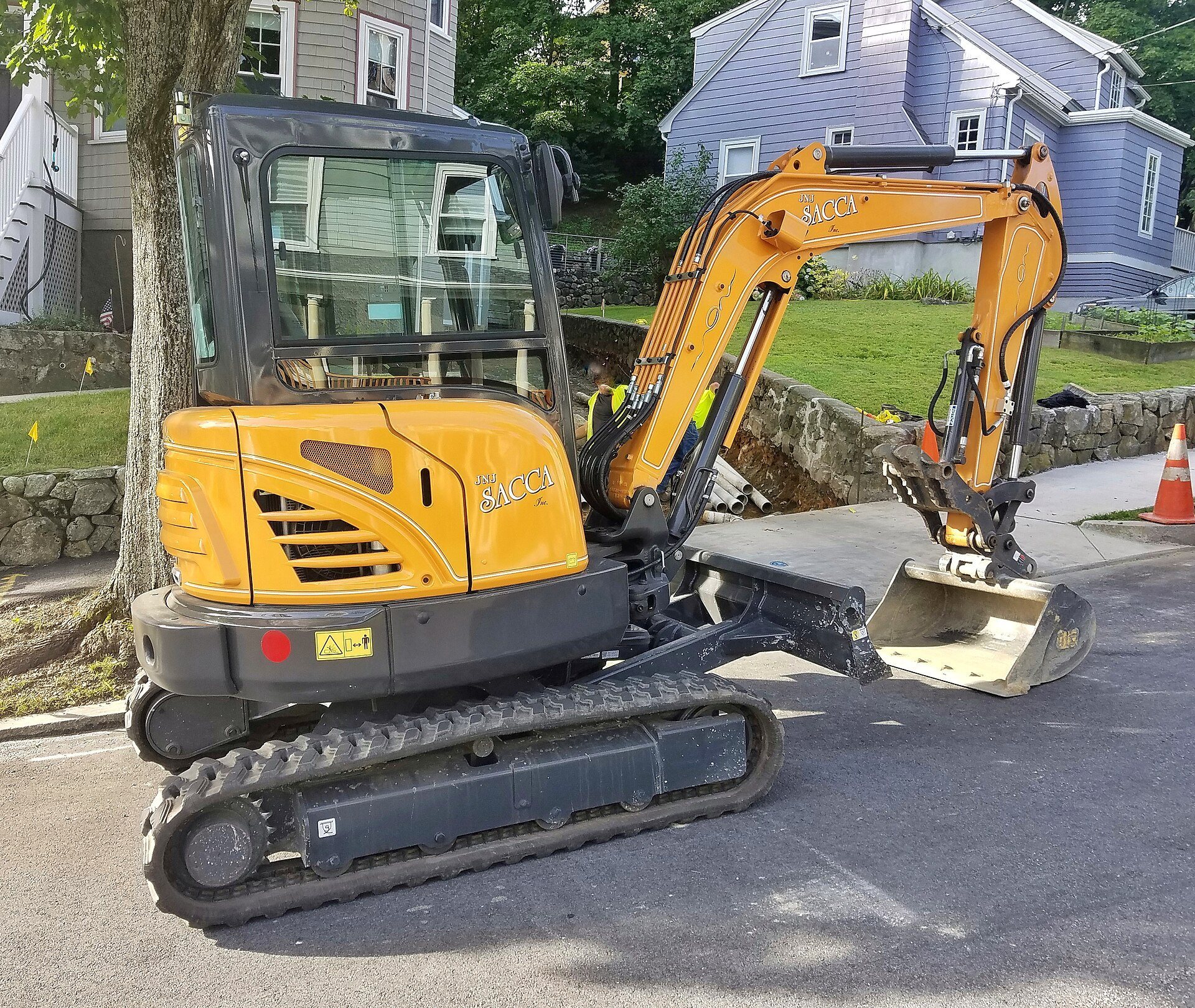 A small yellow Case mini excavator working in a neighborhood
