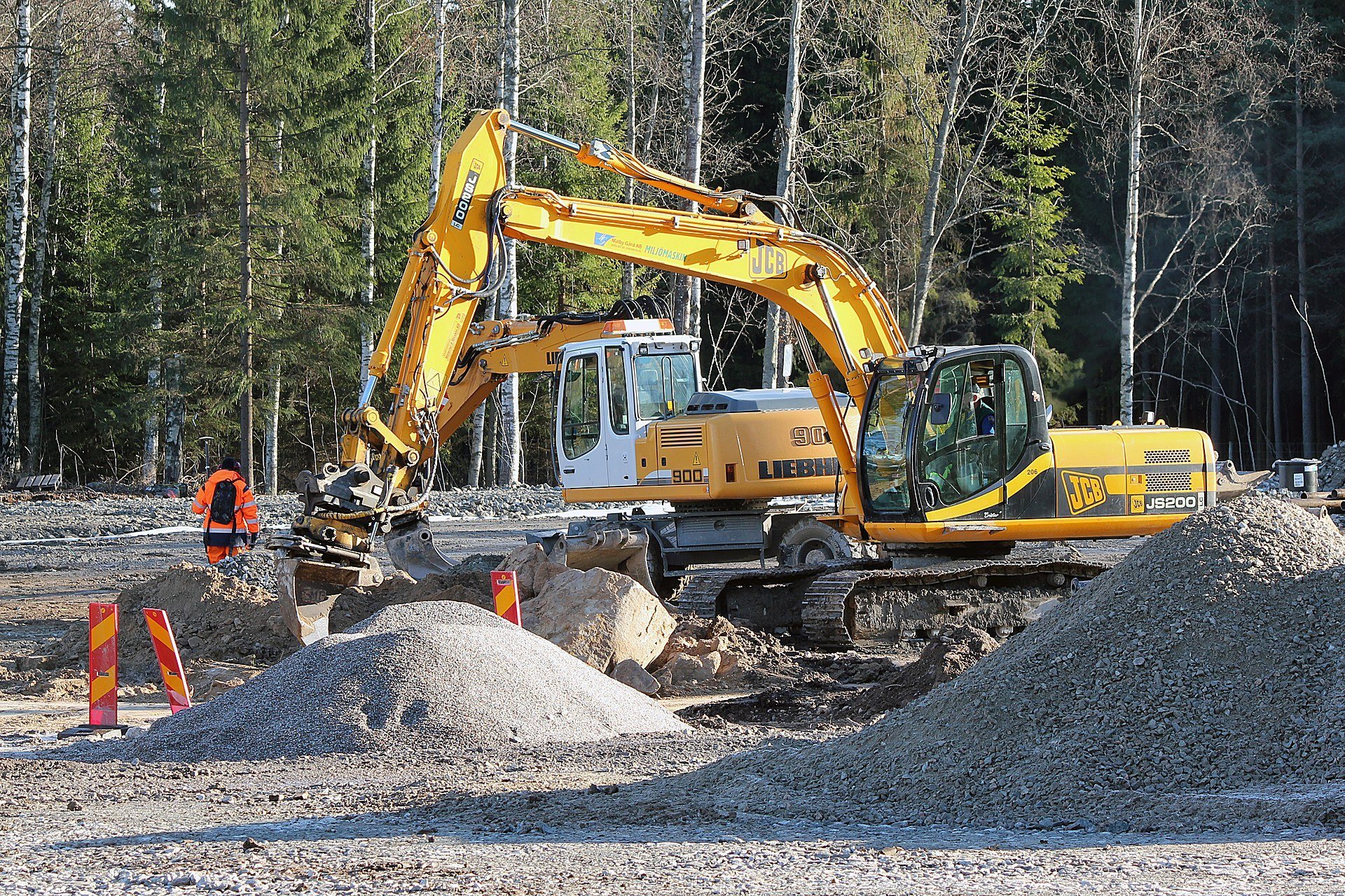 Multiple yellow excavators working together at a road construction site