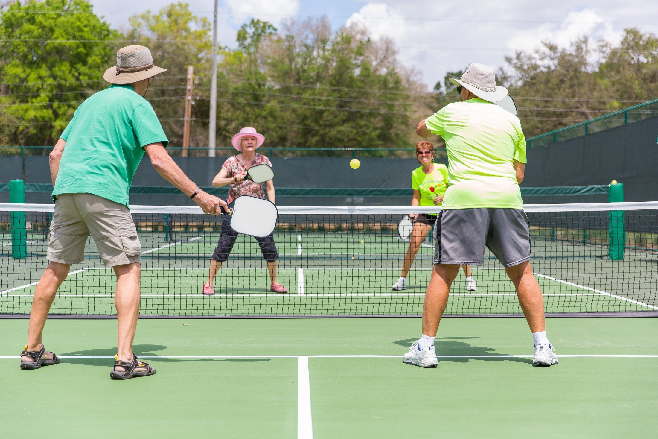 A group of players enjoying a doubles pickleball match on a bright outdoor court, showing the social side of the sport