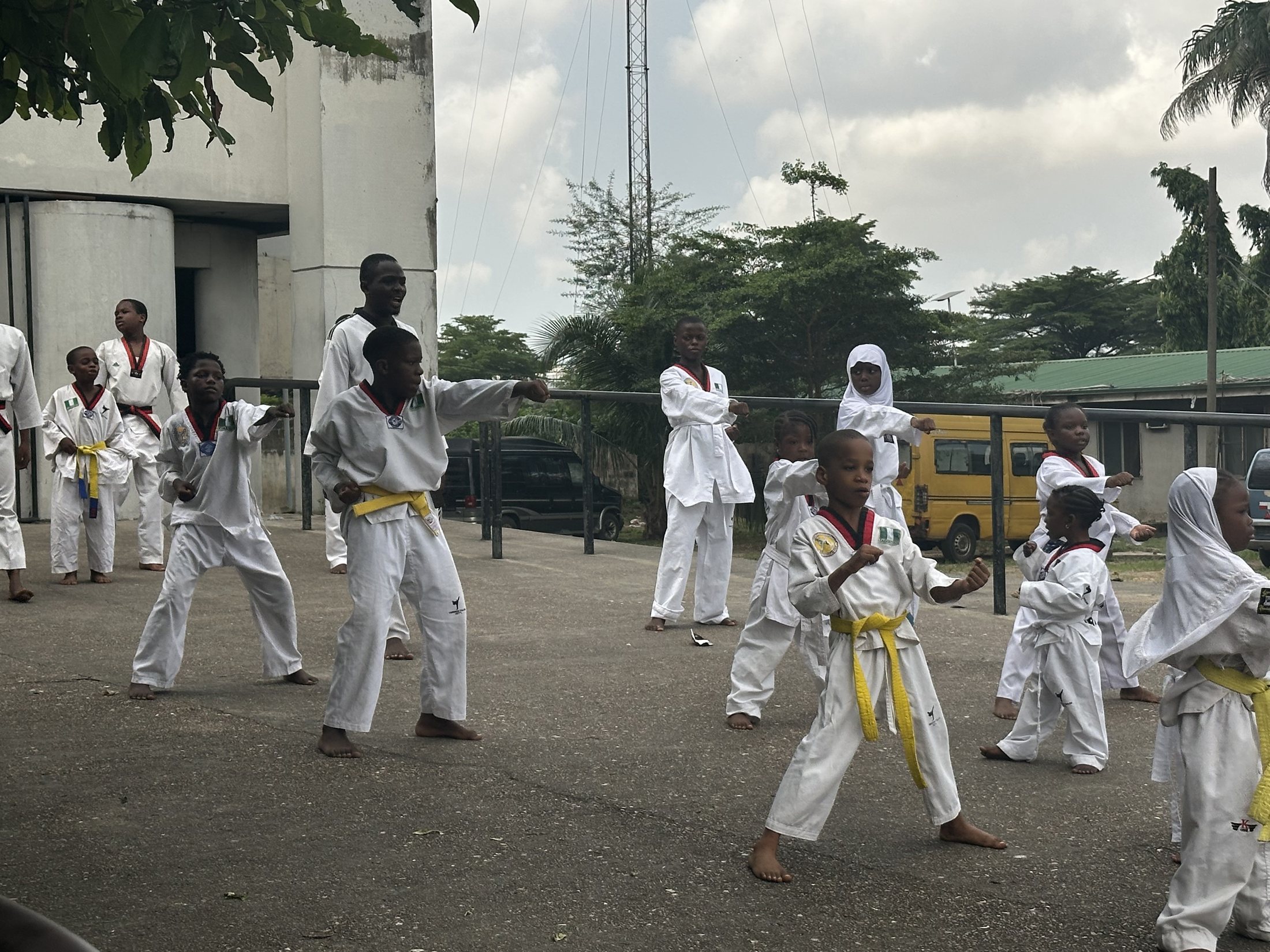 Children in doboks practicing taekwondo movements together during a group activity.
