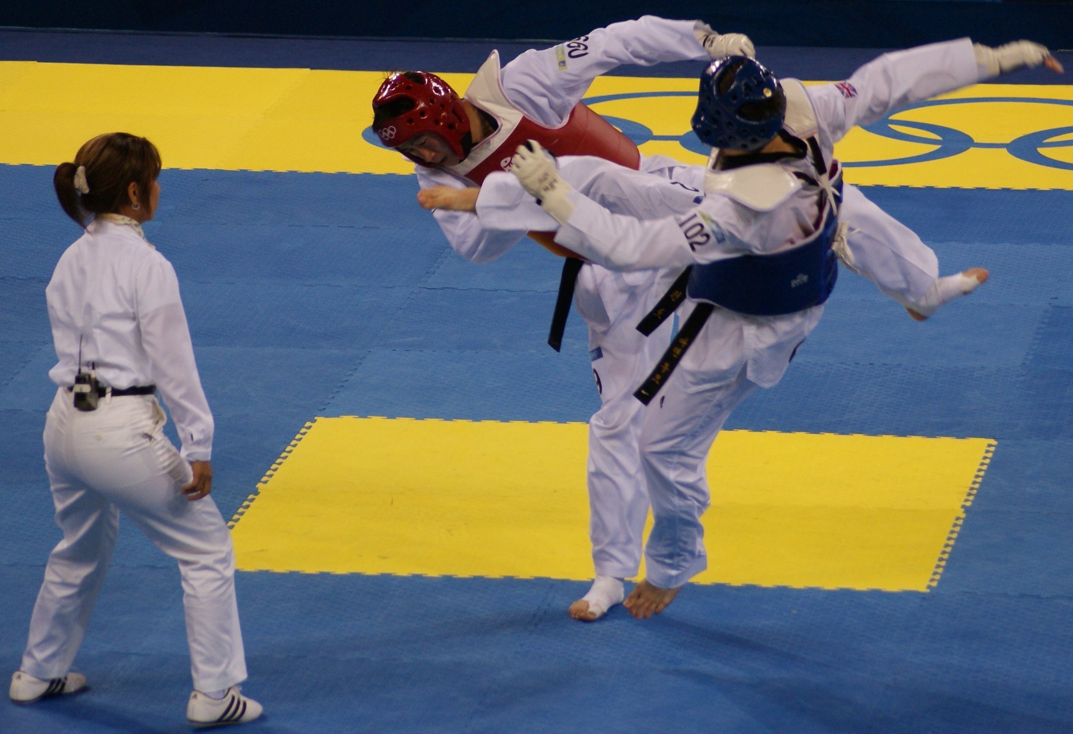 Two Olympic taekwondo athletes sparring in protective gear during a match.