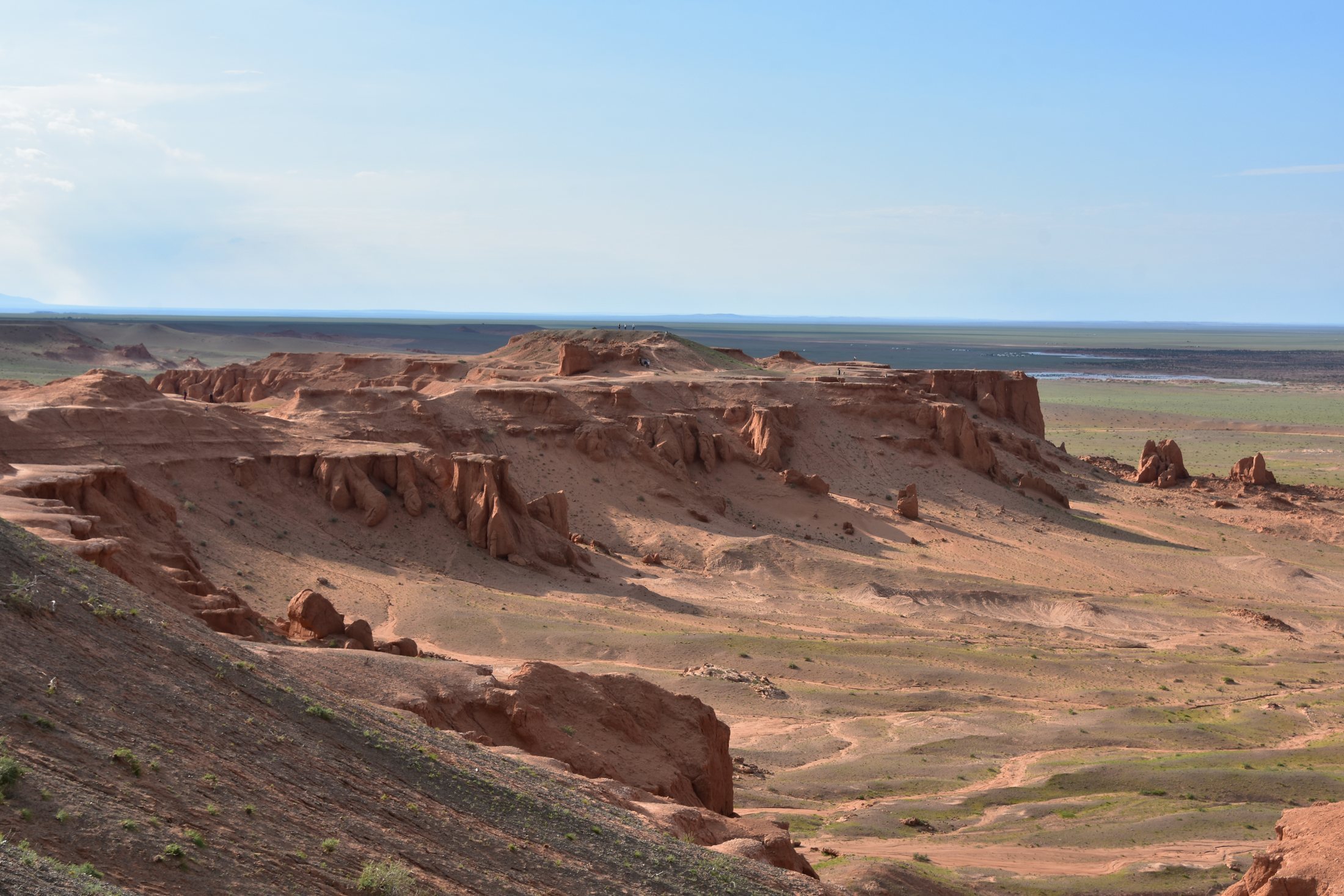 The Flaming Cliffs in Mongolia's Gobi Desert, with red-orange rock formations under a blue sky